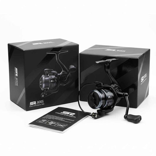 molinete-spinning-wheel-fibra-de-carbono-ultra-leve-preto-com-caixa-e-manual-exibidos-sobre-superficie-branca